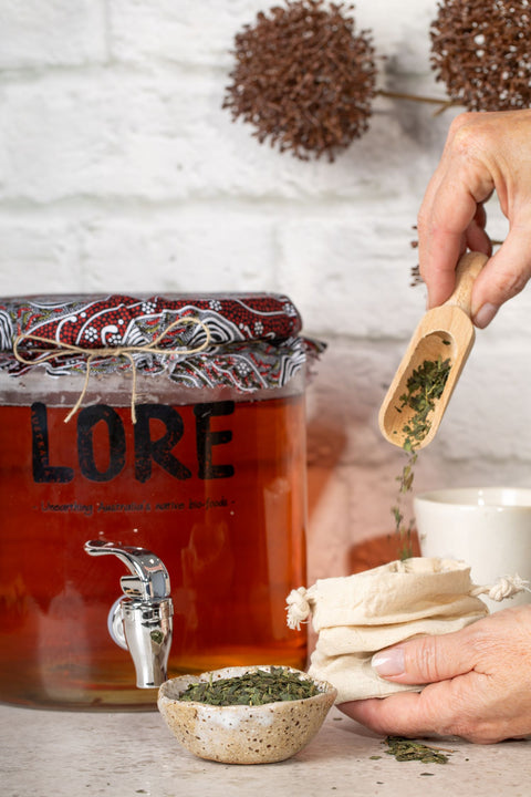 Hands delicately pour Guradji tea into a cloth bag, with a LORE Australia Gurbuchi brewing vessel in the background.