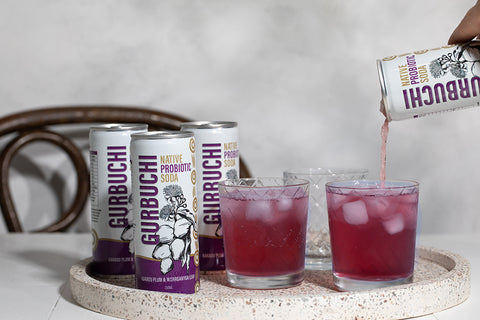 A person pouring a refreshing drink into a glass from a can of Gurbuchi, showcasing the vibrant beverage and the can's design.