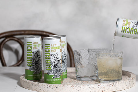 A person pouring a refreshing drink into a glass from a can of Gurbuchi, showcasing the vibrant beverage and the can's design.
