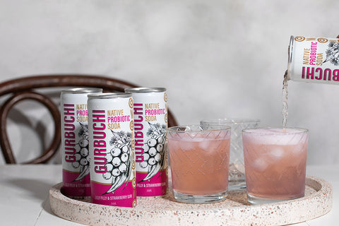 A person pouring a refreshing drink into a glass from a can of Gurbuchi, showcasing the vibrant beverage and the can's design.