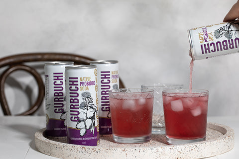  A person pouring a refreshing drink into a glass from a can of Gurbuchi, showcasing the vibrant beverage and the can's design.