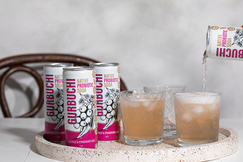  A person pouring a refreshing drink into a glass from a can of Gurbuchi, showcasing the vibrant beverage and the can's design.